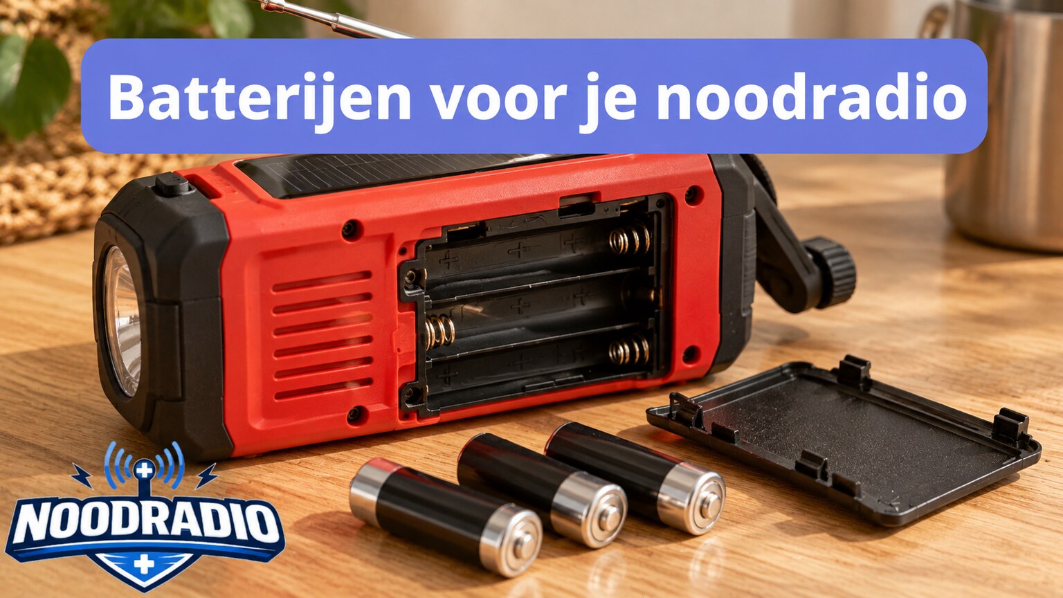 Rode noodradio met een geopend batterijvak en losse AA-batterijen